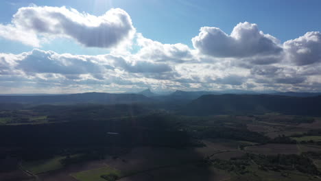 Toma-Aérea-De-Un-Dron-De-Una-Zona-Rural-En-El-Sur-De-Francia-Con-Grandes-Nubes-Blancas-Azules.